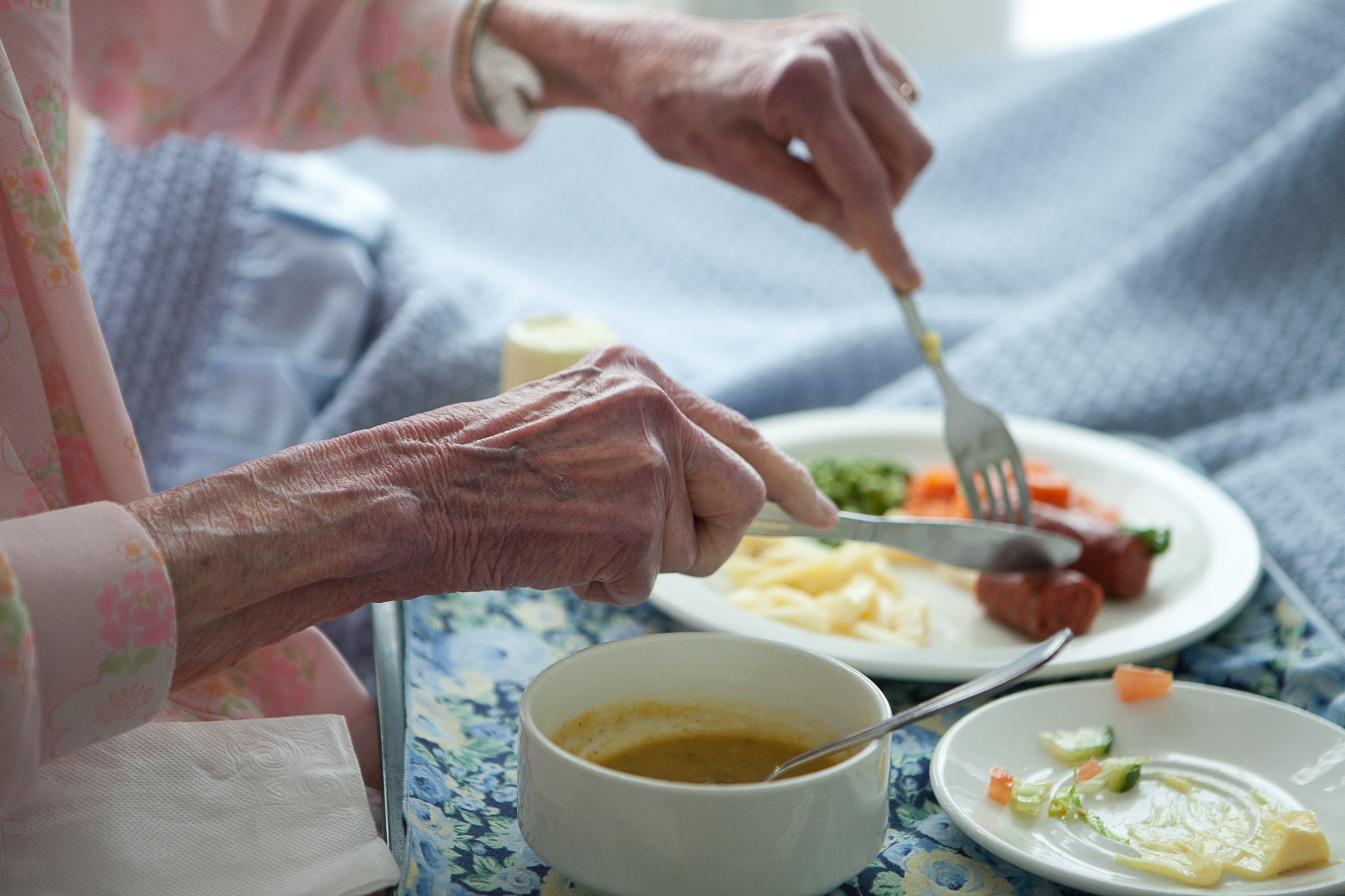 An elderly woman eats a healthy breakfast in bed. Home for the aged. Fragile care. Undernutrition.